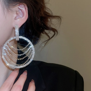 Gros plan de boucles d'oreilles créoles à pompons argentés avec strass sur un mannequin