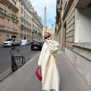 Women's long beige wool coat with a minimalist stand collar in a Parisian street setting