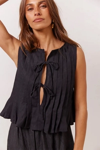 Close-up of black sleeveless pleated top with tie-up detail and linen texture