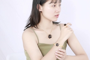 Detail of trendy gold and black daisy jewelry set including necklace and earrings on model