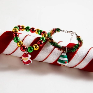 Detail view of festive Christmas bracelets with Santa and tree charms on striped prop