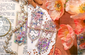 Close-up of holographic PET floral stickers with gold outlines on vintage newsprint