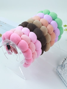 Collection of colorful puffy sponge headbands displayed on an acrylic stand