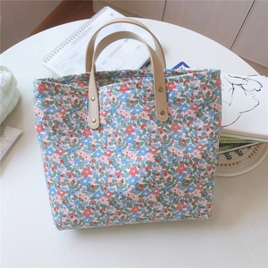 Dettaglio della borsa floreale con rivetti rinforzati e texture del manico in pelle