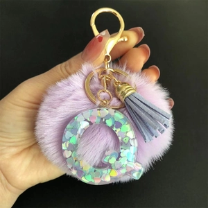 Détail du porte-clés pompon violet avec lettre Q à paillettes holographiques et gland gris