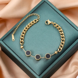 Minimalist gold titanium steel bracelet with three black circular charms on green silk box