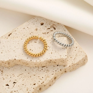 Detailed shot of gold and silver twisted rope titanium steel rings on a beige stone base