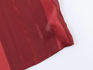 Close-up of red fabric showing subtle vertical stripes and lightweight sheer texture
