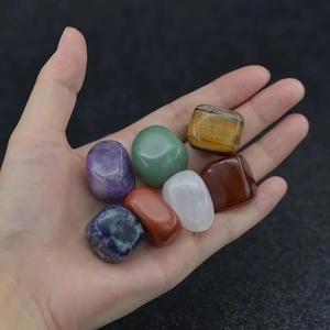 Hand holding set of 7 natural chakra tumbled stones including amethyst and tiger eye