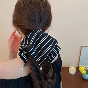 Chouchou rayé en tissu avec perles sur mannequin dans un intérieur chaleureux