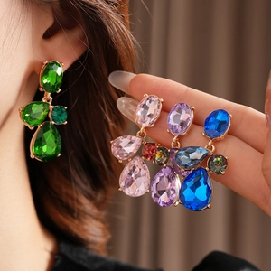 Detailed view of colorful teardrop crystal earrings in vintage gold-tone settings