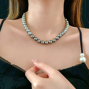 Detail of elegant black pearl necklace worn on model featuring deep metallic luster finish