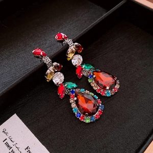 Macro shot of colorful drop earrings with a pear-cut red crystal and multi-color rhinestones