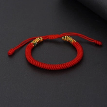Detailed view of red woven cotton bracelet with gold accents and adjustable sliding knot