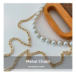 Detail of gold metal chain, white pearls with rhinestones and wooden handle for handbag