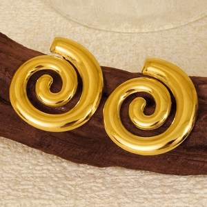 Close-up of golden geometric spiral conch earrings on a vintage wooden prop