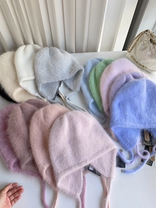 Detailansicht flach liegender Angora-Kaninchenfell-Mützen in verschiedenen Pastellfarben