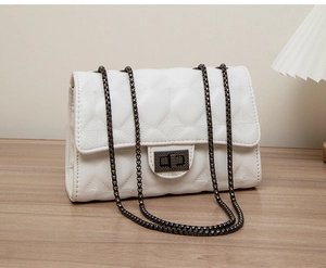 Detailed view of white quilted crossbody bag with metal chain strap and twist lock