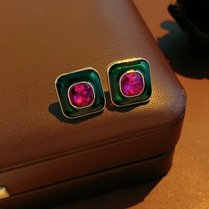 Detail of vintage square emerald enamel earrings with rose red crystal on leather
