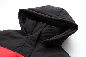 Détail de veste d'hiver à capuche montrant les coutures rouge et noir et le col