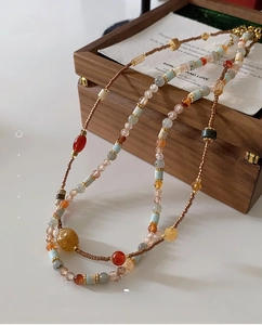 Detailed close-up of double-layered beaded necklace with red agate and natural stones