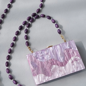 Detail of purple marble acrylic clutch bag with matching beaded resin shoulder strap