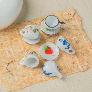 Close-up of miniature ceramic teacups and saucers with floral patterns for jewelry making