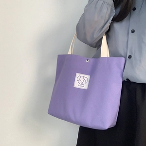 Detail of purple canvas tote bag featuring a cute cartoon dog patch and lovable text