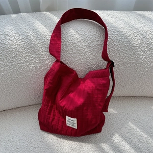 Detailed texture of vibrant red pleated canvas tote bag on a soft white sofa surface