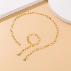 Minimalist gold metal O-chain jewelry set featuring a necklace and bracelet on geometric props