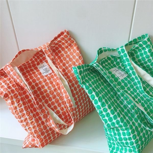 Detail view of colorful cotton tote bags featuring a geometric circular pattern and inner tags