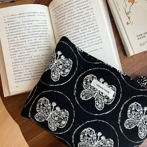 Détail de la broderie papillon sur pochette en toile noire avec étiquette en tissu