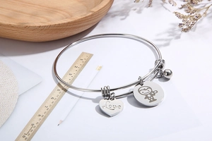 Silver stainless steel love heart and monkey charm bracelet on a wooden ruler for scale