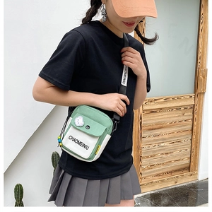 Detail of green and white canvas crossbody bag with branded strap worn by model