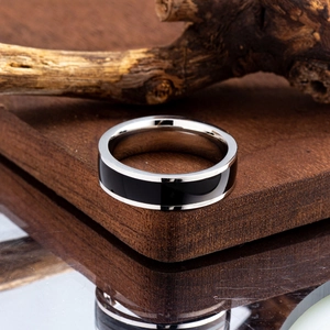 Modern two-tone stainless steel ring detail on a dark wooden block with mirror reflections