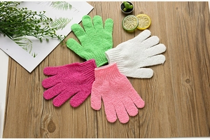 Flat lay of colorful exfoliating shower gloves on a wooden background with lemons