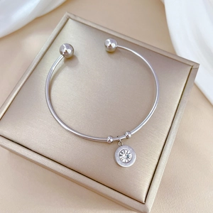 Macro detail of silver titanium steel bangle with Roman numeral zircon pendant