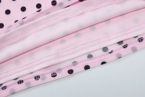 Detail of pink mesh fabric with black polka dots and high-quality stitching on camisole