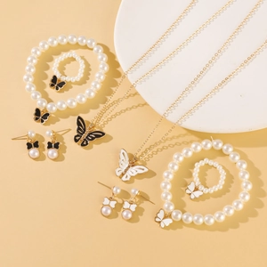 Set di gioielli dorati con collane di perle, ciondoli a farfalla, bracciali e anelli