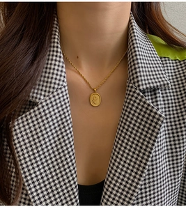 Detailed close-up of a vintage golden sunflower pendant necklace on a houndstooth blazer
