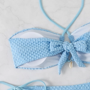 Detail of light blue seersucker bikini top with bow and natural seashell pendant decoration
