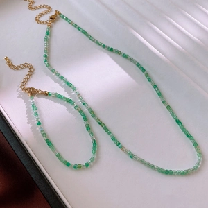 Detail of green beaded necklace and bracelet set with golden lobster clasp and chain