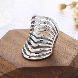 Detail of silver layered hollow wavy line steel ring on a geometric wooden base