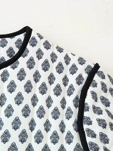 Detail view of ethnic leaf print quilting fabric with black binding on white cotton coat