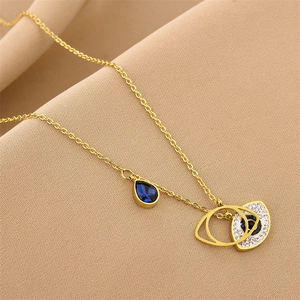 Gold Evil Eye necklace with deep blue drop stone and micro-diamonds on textured background