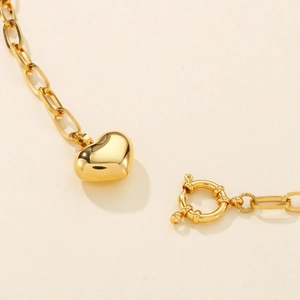 Detail of golden heart pendant on square link chain with round spring clasp closure
