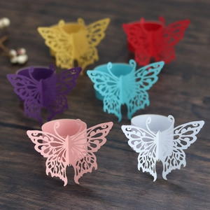 Detailed laser-cut butterfly napkin rings in multiple colors on a dark wood table