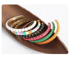 Close-up of colorful enamel gold-plated hoop earrings on a vintage wooden tray