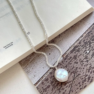 Detail of S925 silver chain with a large baroque pearl on vintage paper background