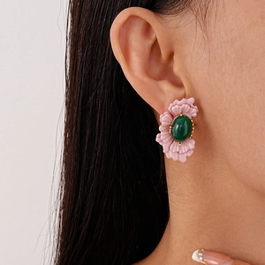 Vintage floral stud earrings with pink petals and green gemstone worn by a model